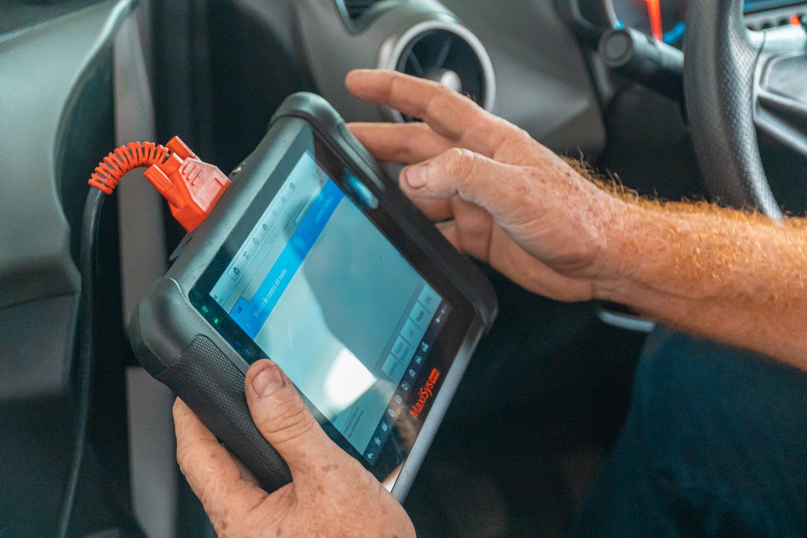 Un mécanicien utilise une tablette de diagnostic branchée sur un véhicule