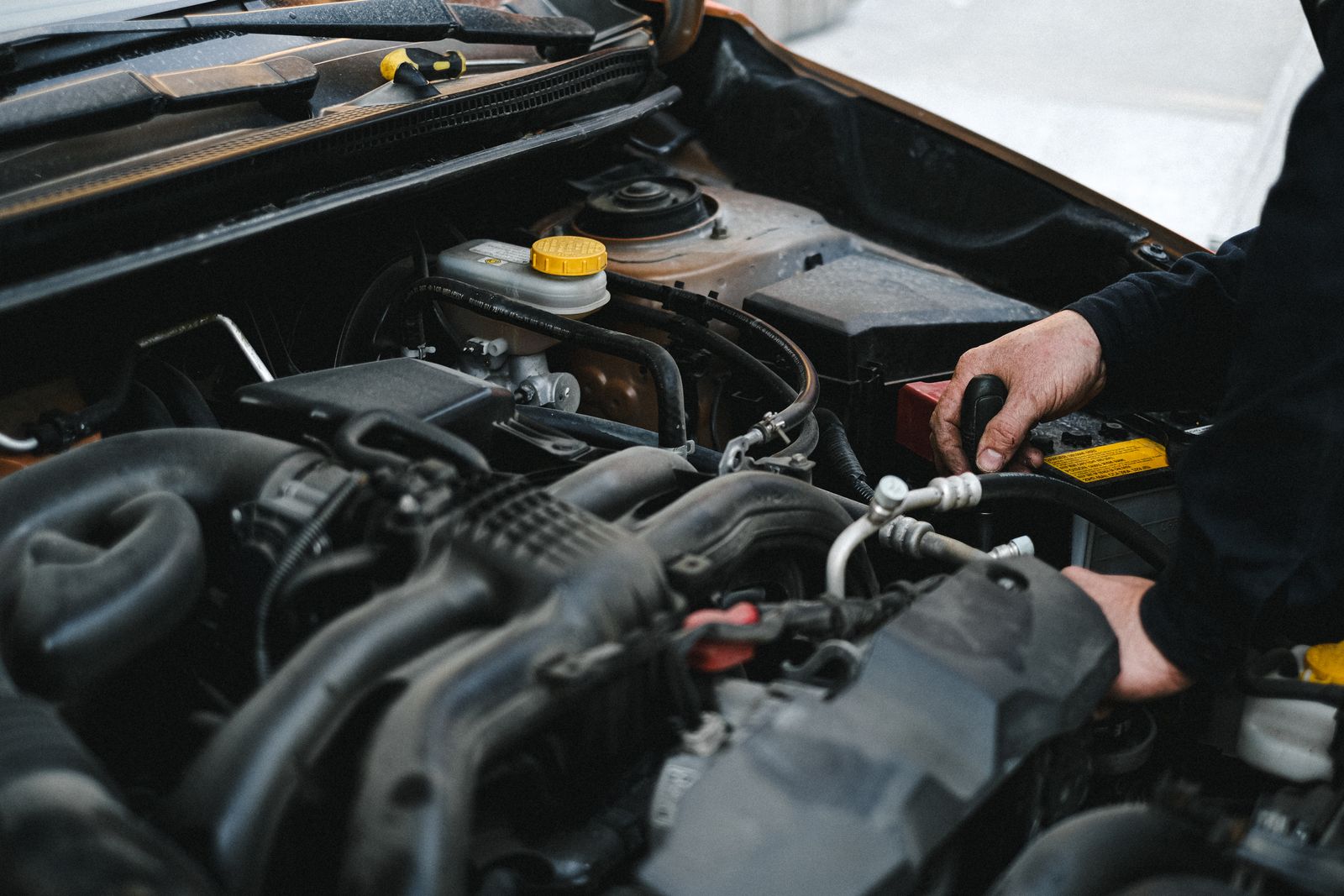 Les mains d'un mécanicien travaillent dans un compartiment moteur