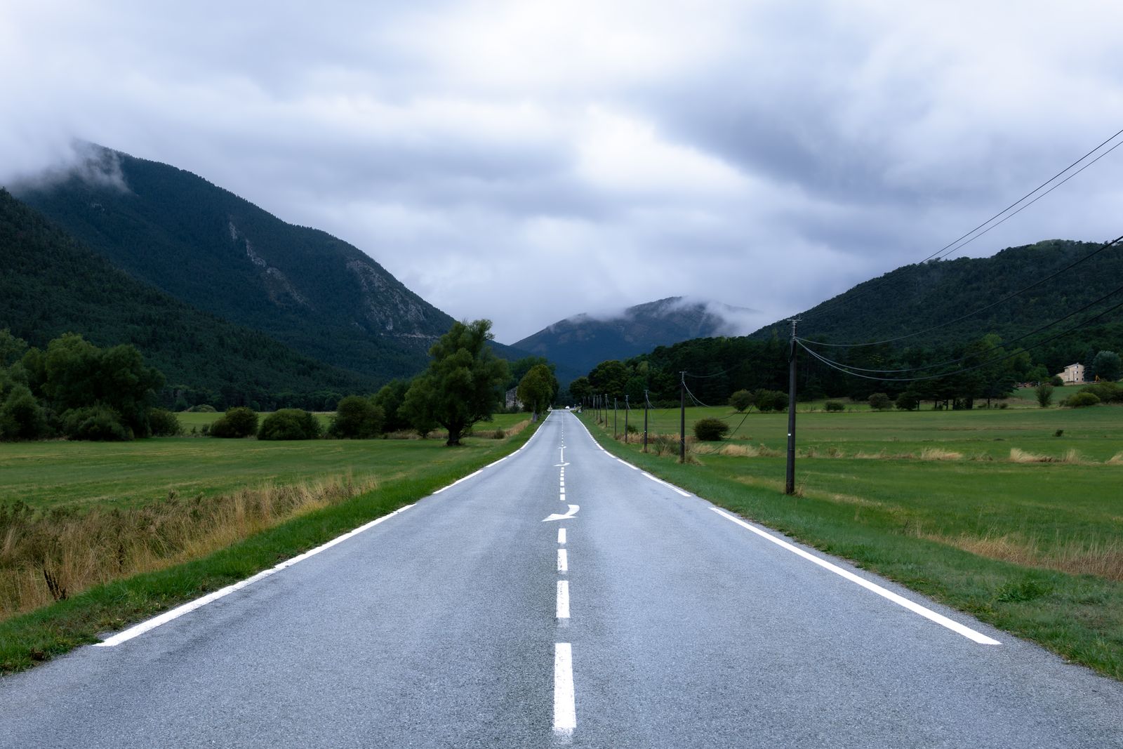 Route de montagne déserte en direction des Alpes sous un ciel nuageux
