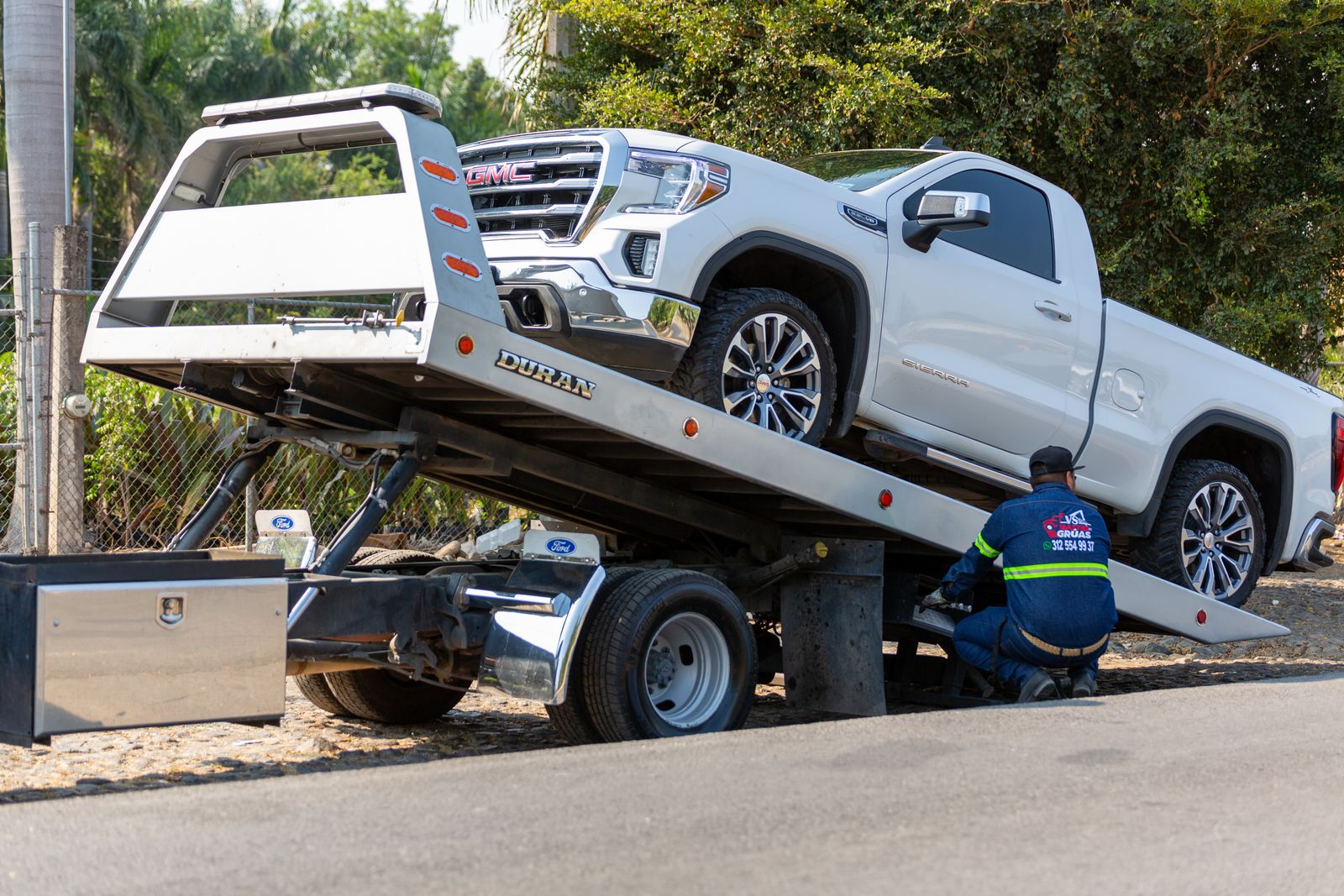 Une dépanneuse charge un pick-up blanc sur son plateau